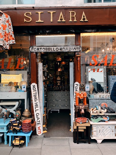 The storefront of Sitarra, a shop on Portobello Road in Notting Hill, features a wooden sign with the name in gold lettering above the entrance. The shop's entrance is open, revealing an interior fill